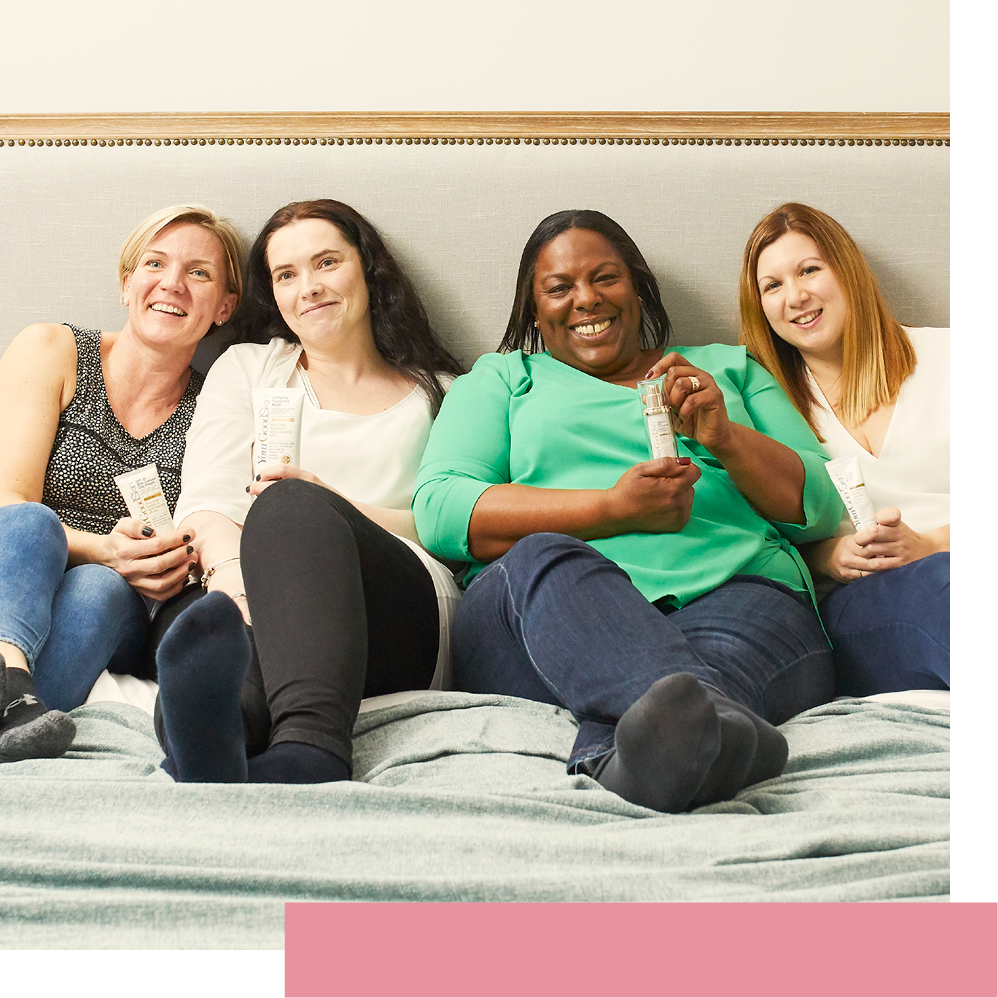 Four women on a sofa smiling at the camera