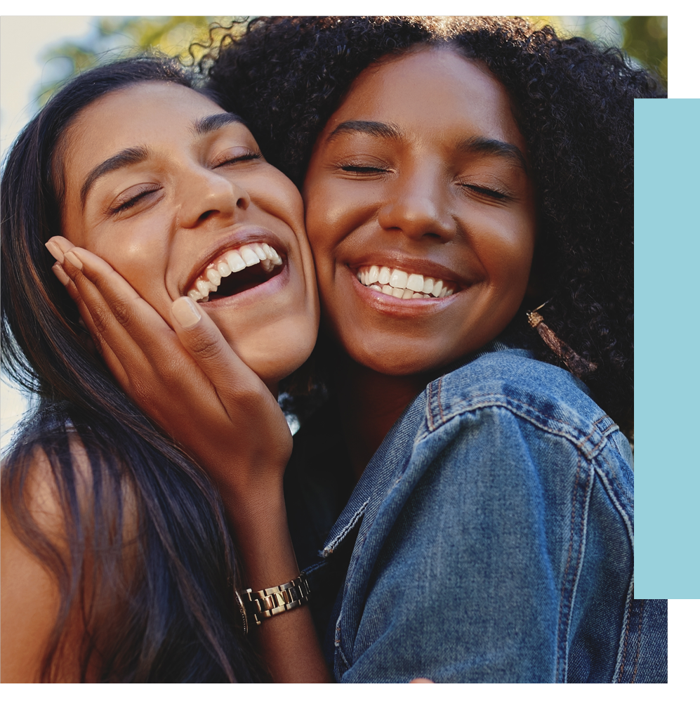 Close up lifestyle portrait of diverse multiracial happy best friends hugging each other and laughing in the park