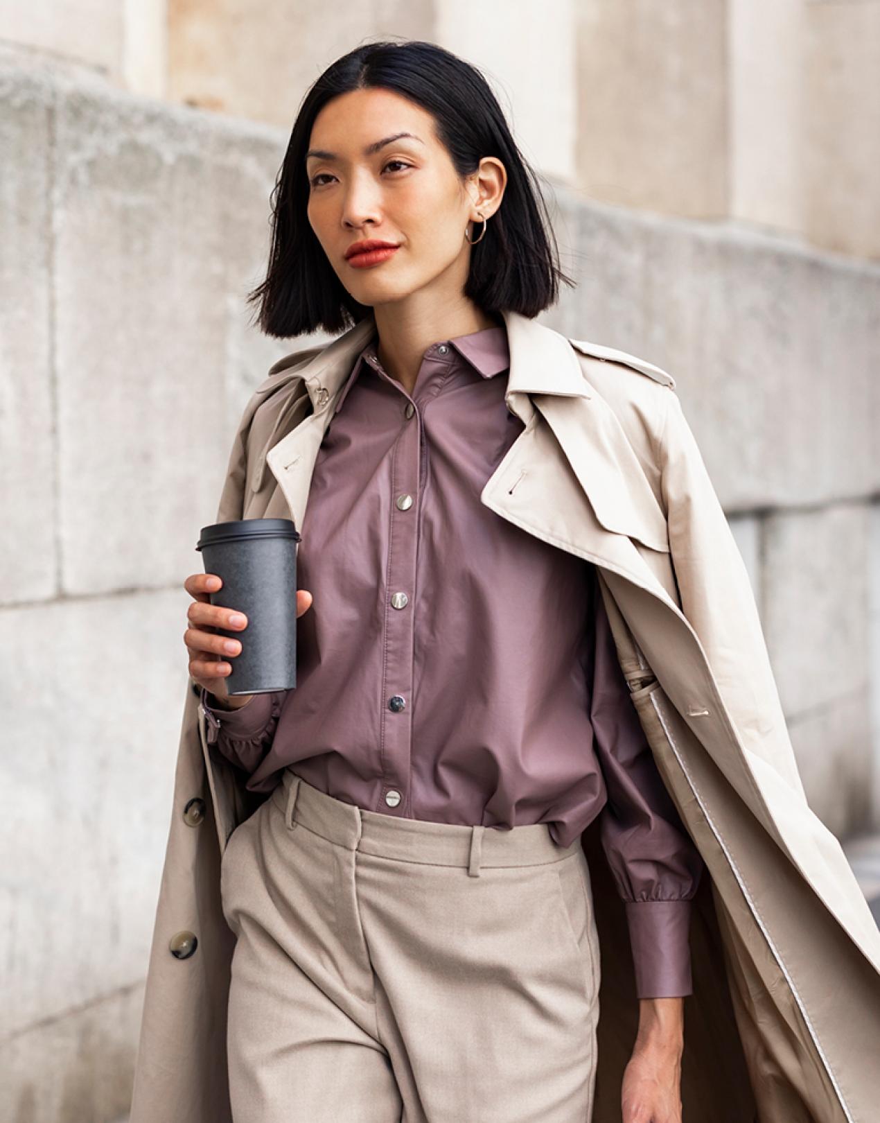 A woman walking and holding a cup of coffee