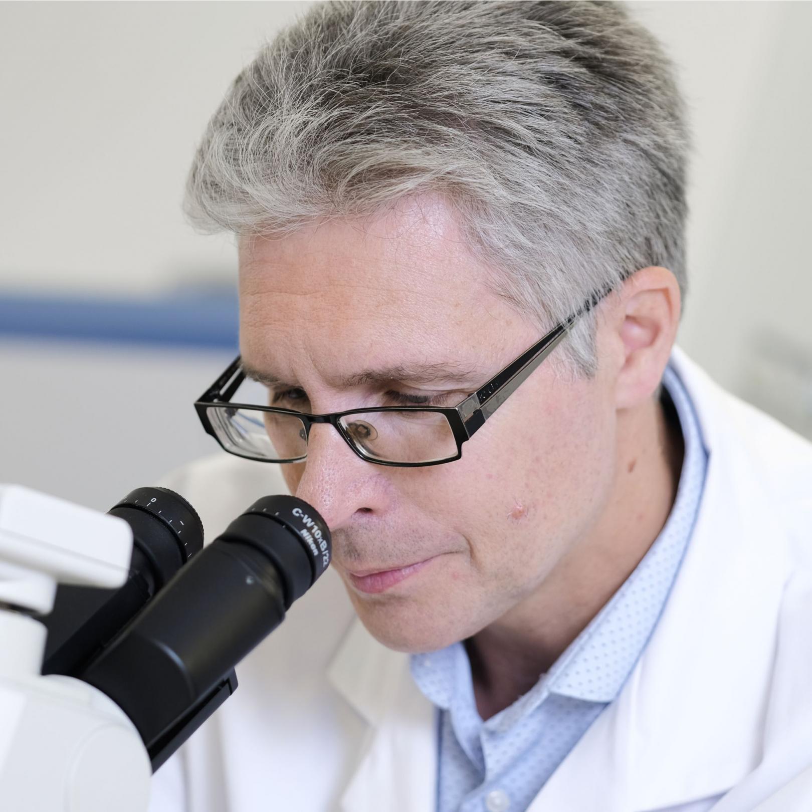 Photo of Dr Mike Bell looking into a microscrope